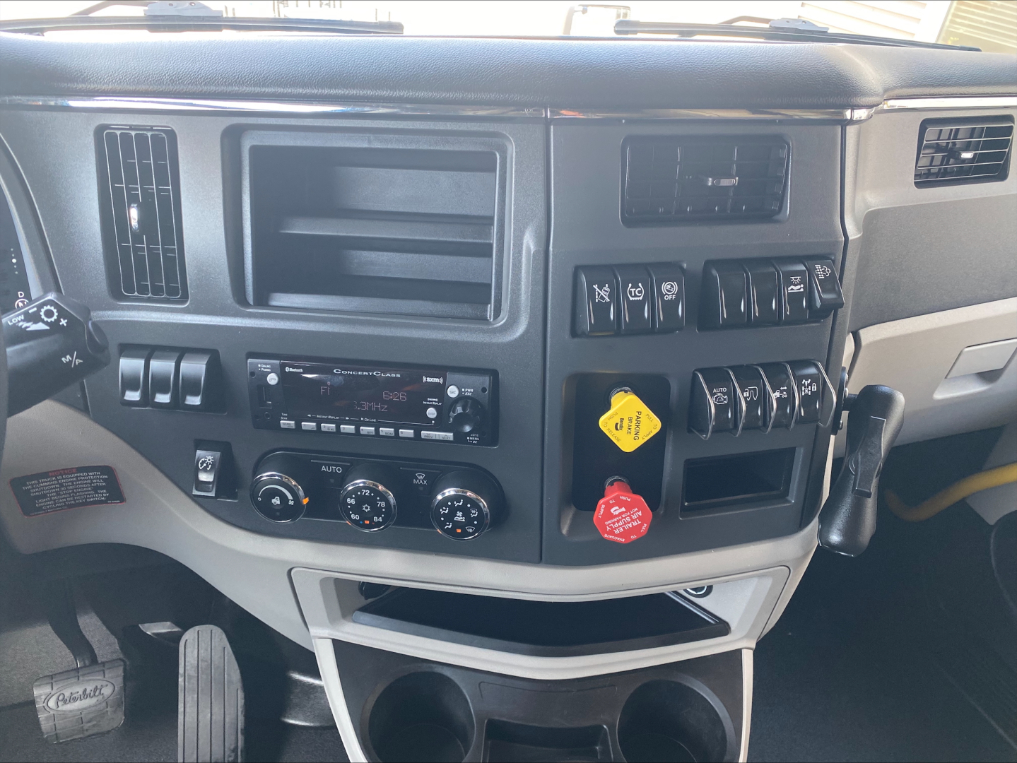 Peterbilt 579 truck cockpit dashboard view with control switches, vents, and cup holders.