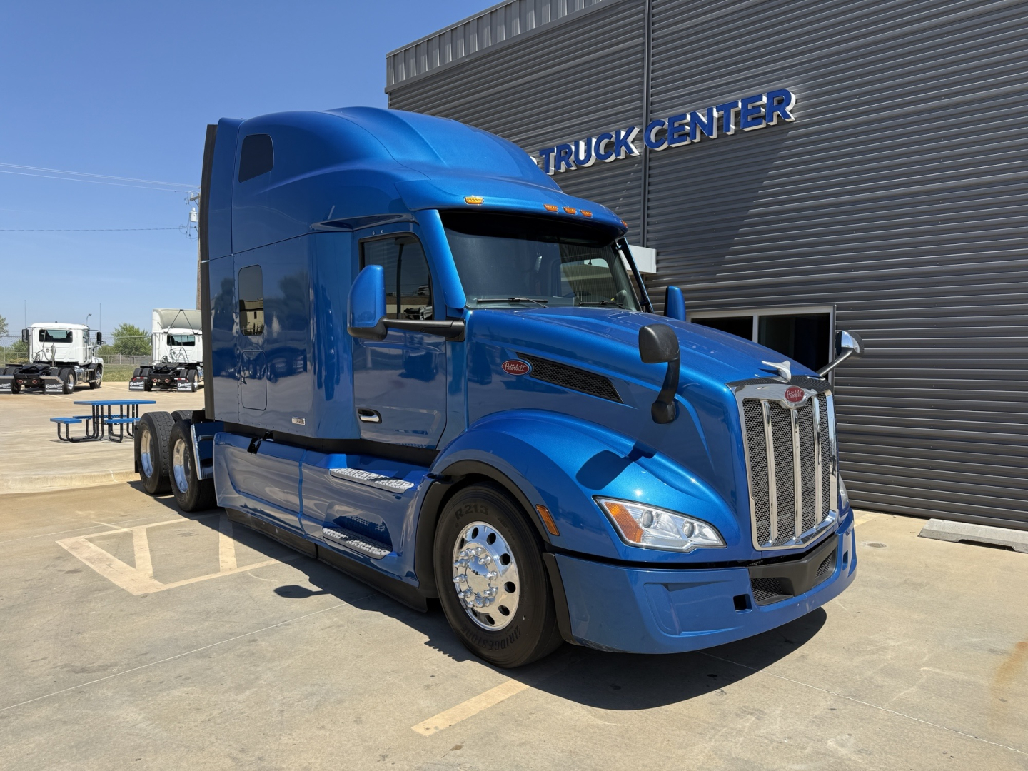 Peterbilt 579 conventional sleeper tractor in blue, front/driver-side view showing cab and chrome grille.