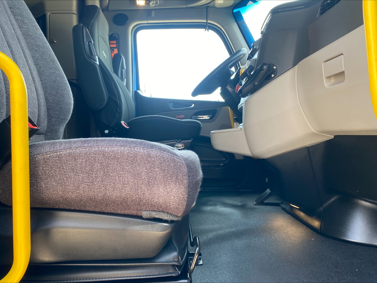Peterbilt 579 truck cab interior view showing driver seat, steering wheel, and dashboard with grey accents.