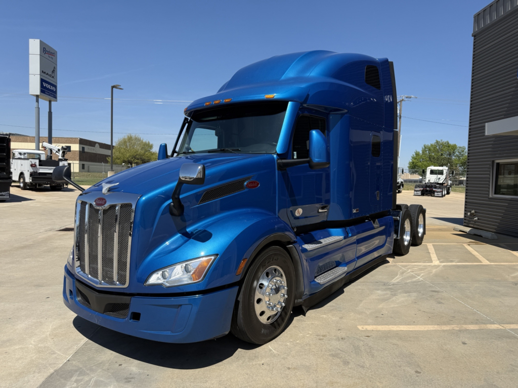 Blue 2022 Peterbilt 579 conventional sleeper truck shown curbside, front-left angle. Visible text includes Peterbilt logo on grille and no other legible labels.