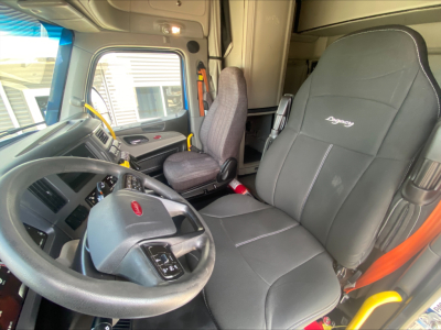 Truck cabin interior of a 2022 Peterbilt 579 showcasing driver seat and dashboard area with steering wheel and plush seating.