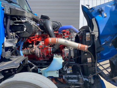  peterbilt 579 engine bay showing diesel engine with red and blue hoses, intake, coolant reservoir, and open hood