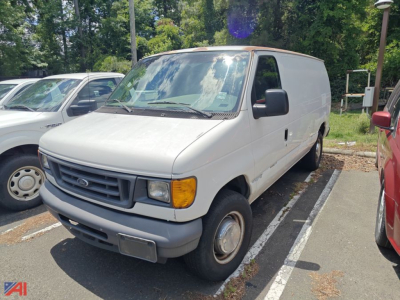 Ford E-Series cargo van in a parking lot, front-left view, white exterior, grey bumper, black side mirrors