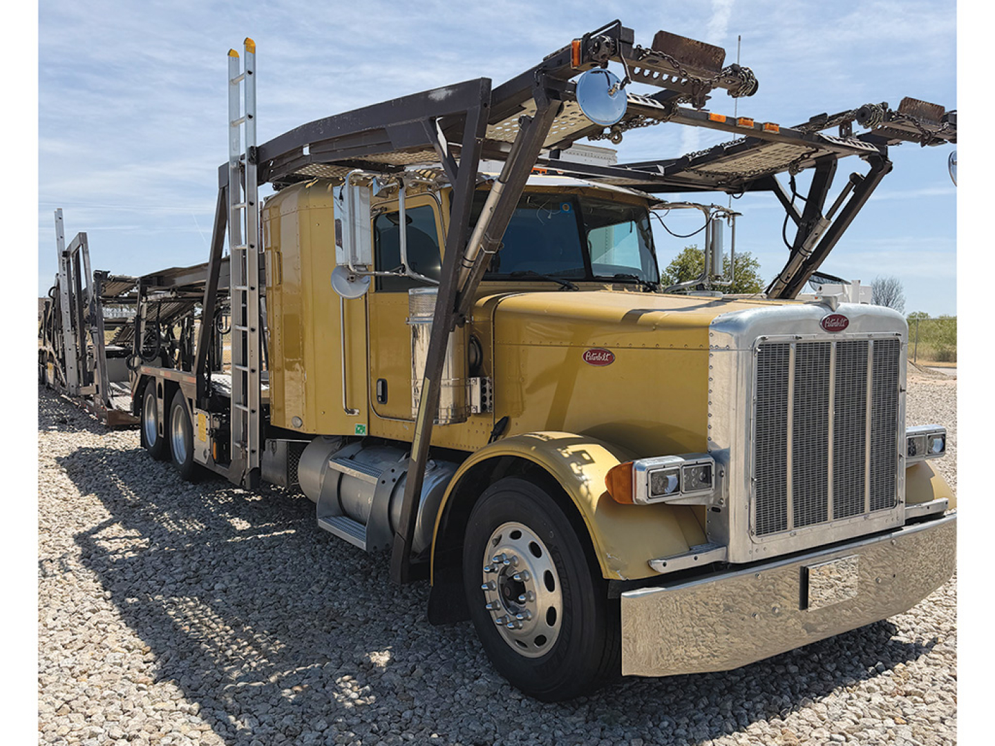 Peterbilt 379 truck with flatbed car carrier equipment on the back, yellow cab, chrome grille, and heavy-duty bumper