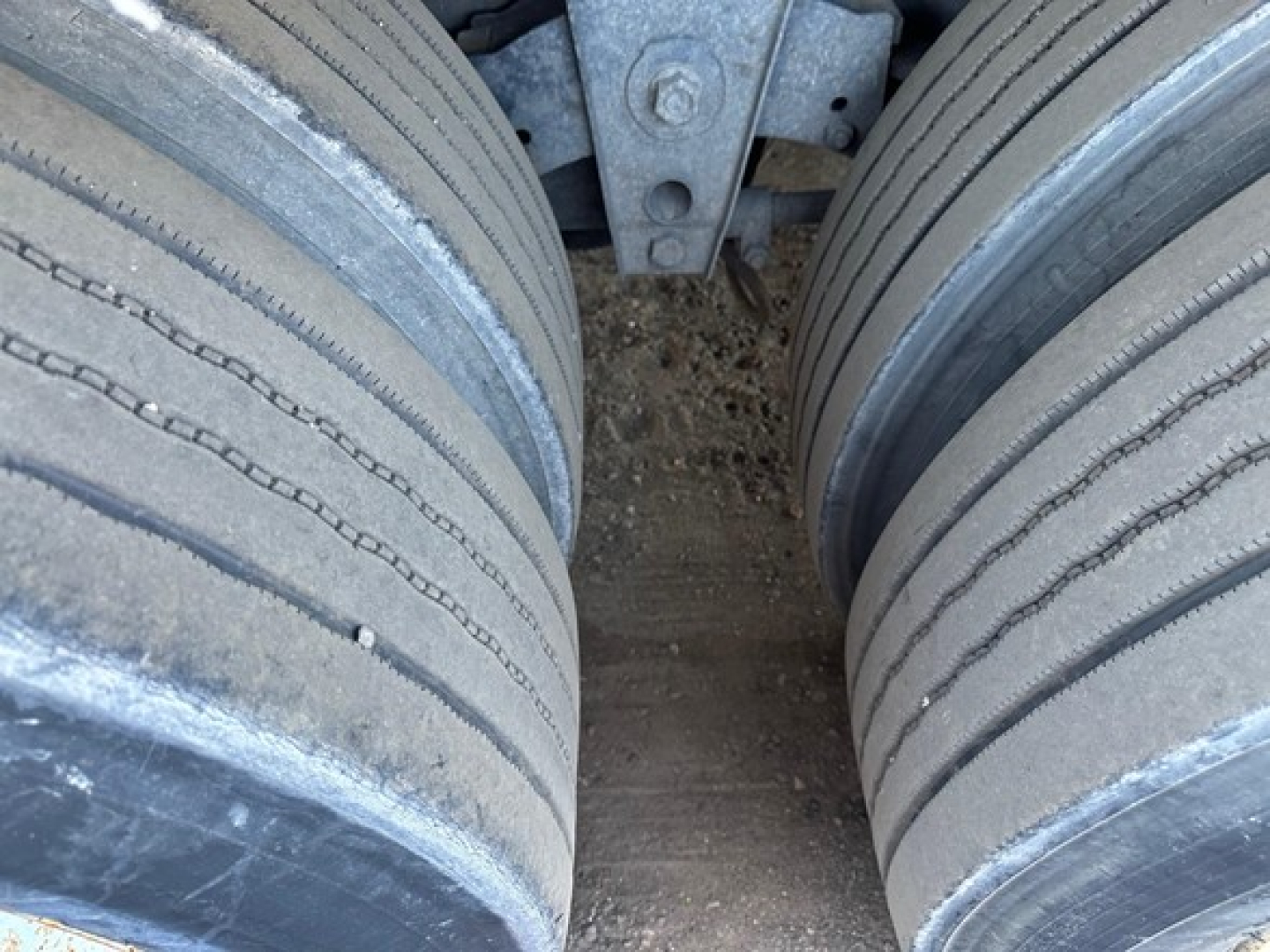 Dual rear tractor tires on a flatbed trailer with metal frame in background
