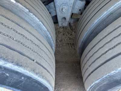 Dual rear tires of a trailer with metal frame and leaf spring visible between them.