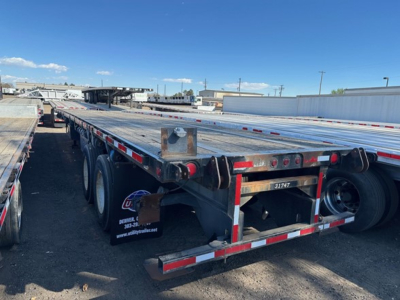 Flatbed trailer with steel 45' forklift kit in yard showing rear and side rails and wheels.