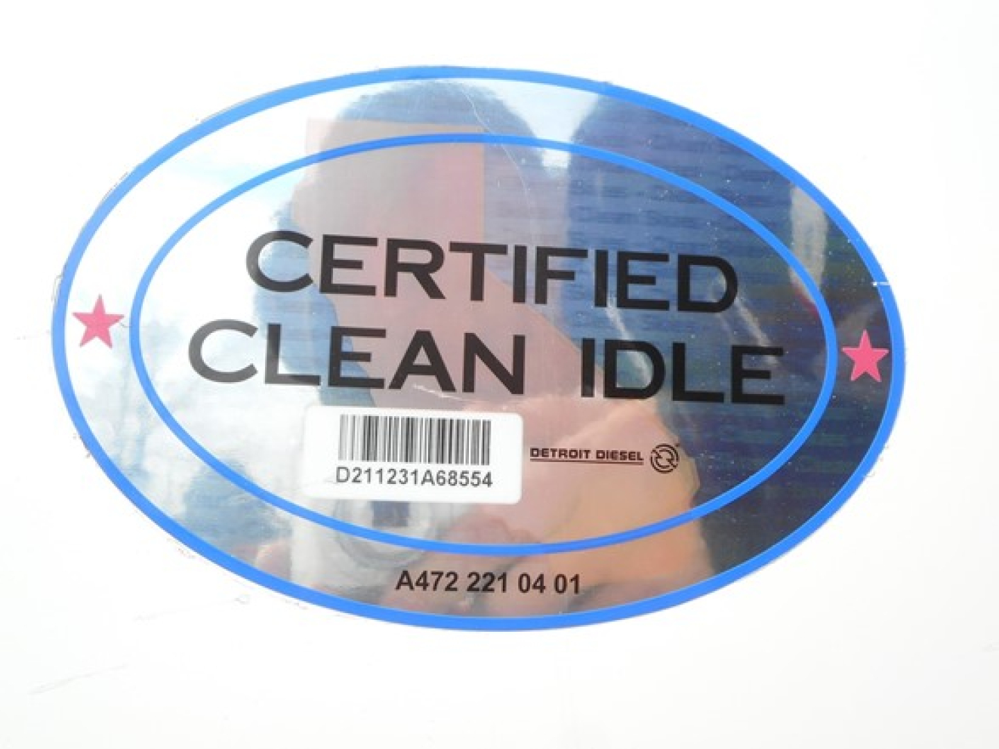Sticker reading CERTIFIED CLEAN IDLE with a barcode and detroit diesel logo underneath, oval blue border with stars.