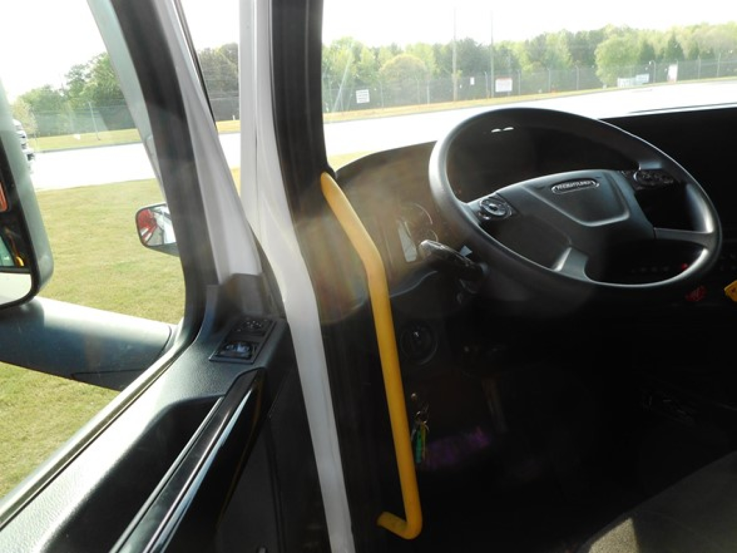 Truck cabin interior from driver side with steering wheel and dash visible.