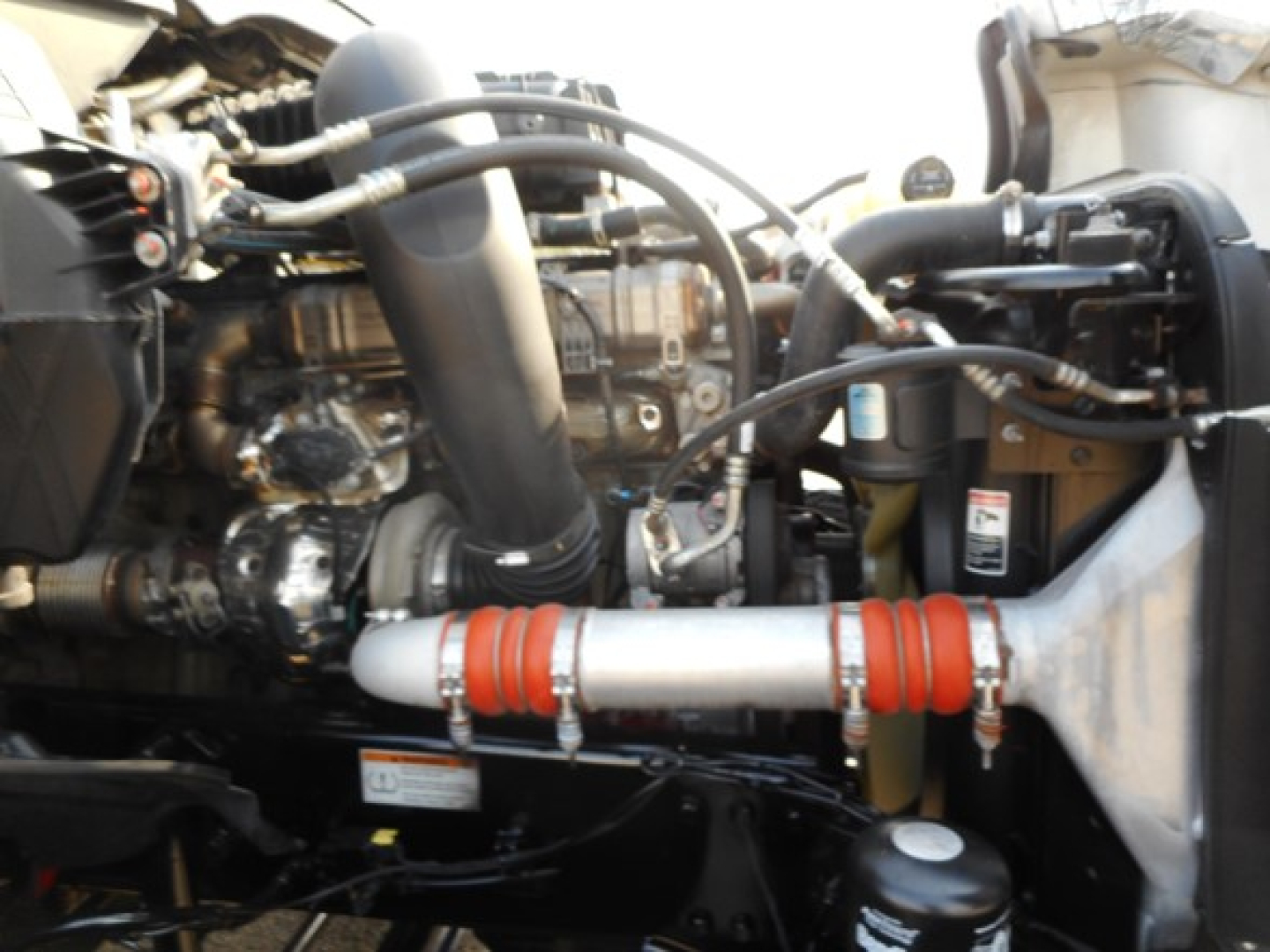 Engine bay of a Freightliner Cascadia 126 showing hoses, intercooler pipe, and various components