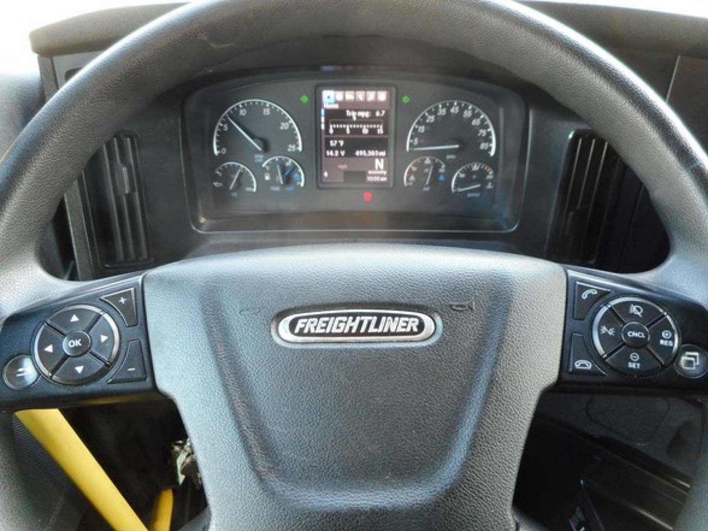 Dashboard view of a Freightliner Cascadia 126 steering wheel with instrument cluster visible and control buttons on both sides.