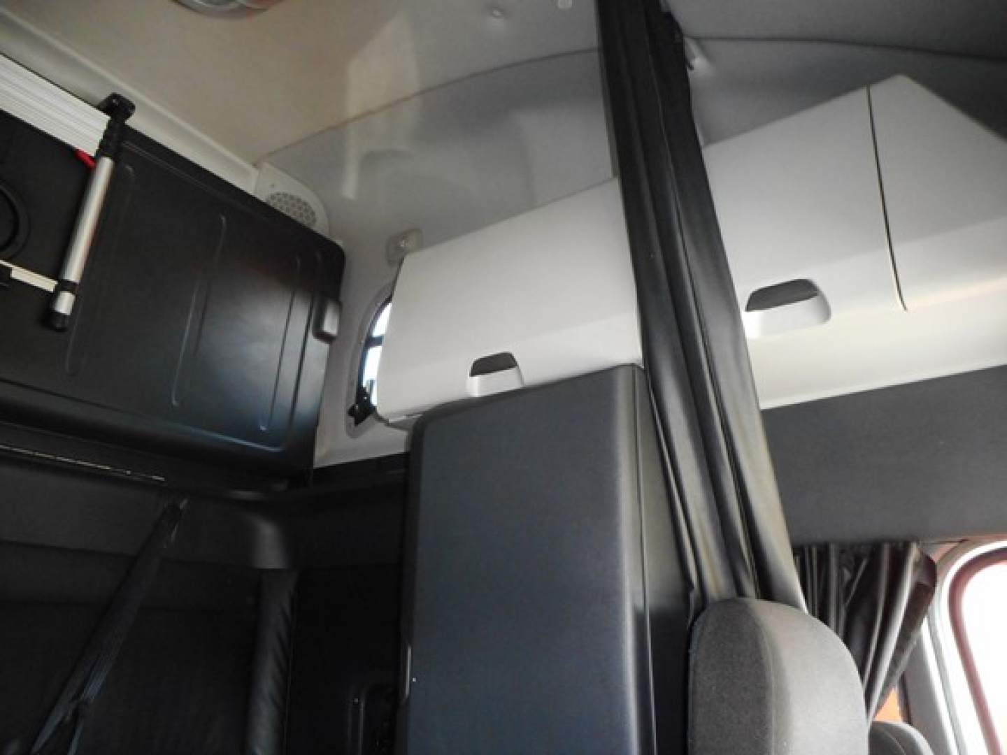 Cab interior of a Freightliner Cascadia showing storage compartments and seating area.