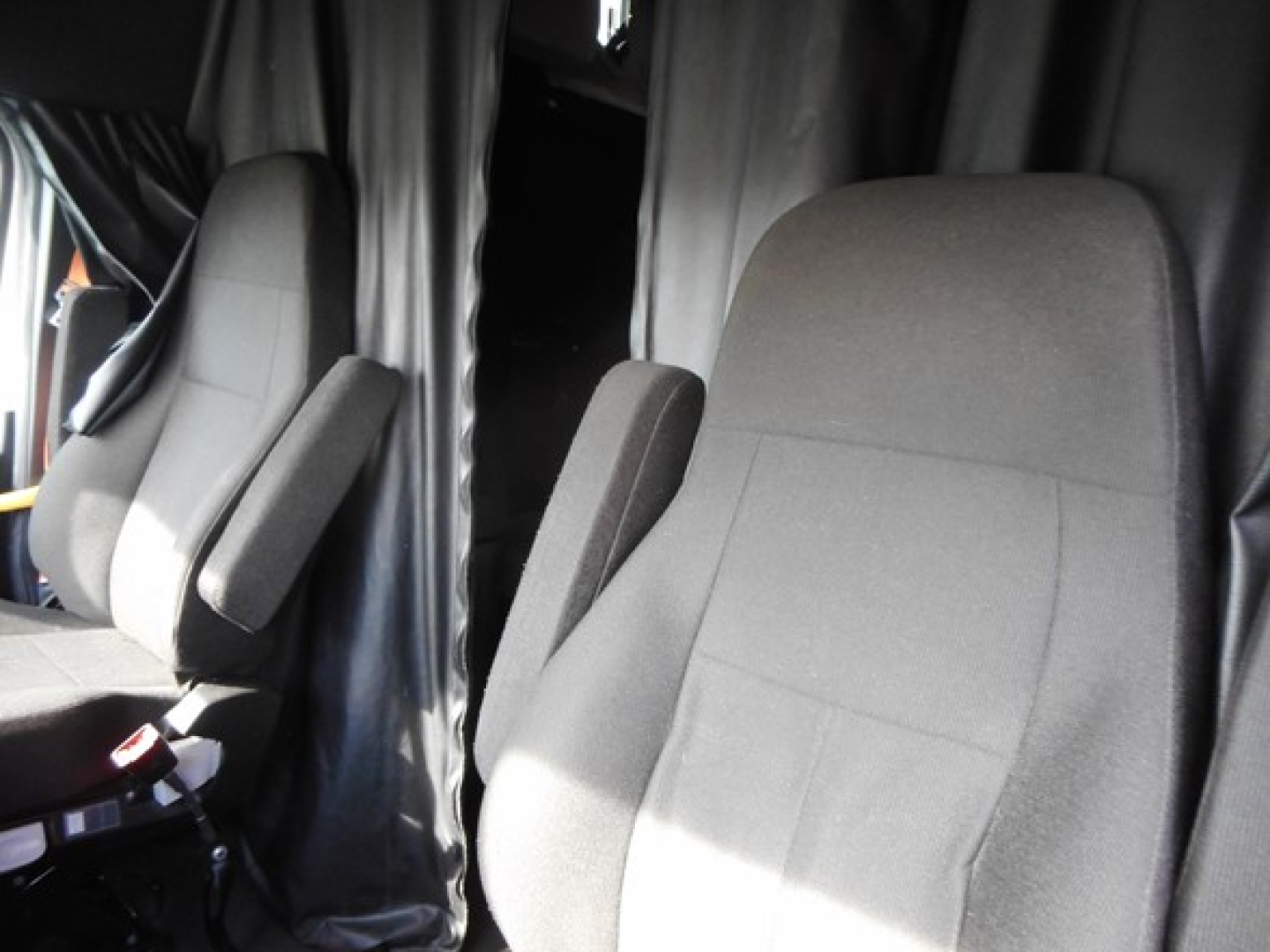 Cab interior showing two front seats in a Freightliner Cascadia sleeper cab.