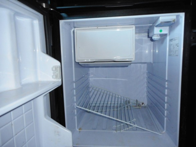 Frigidaire? no image shows a Freightliner Cascadia 126 fridge/freezer in cabin? Wait. It shows empty small refrigerator/freezer unit inside a sleeper truck with metal shelf racks.