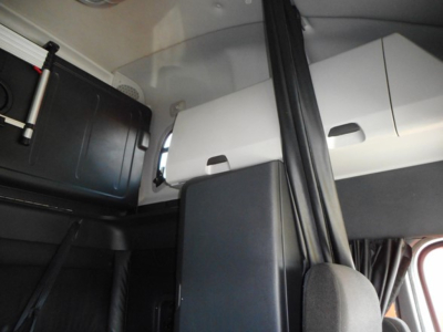 Cab interior of a Freightliner Cascadia showing storage compartments and seating area.