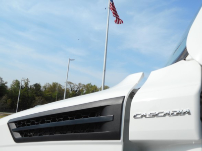 Truck front quarter showing Cascadia badge on white Freightliner Cascadia 126 sleeper tractor.