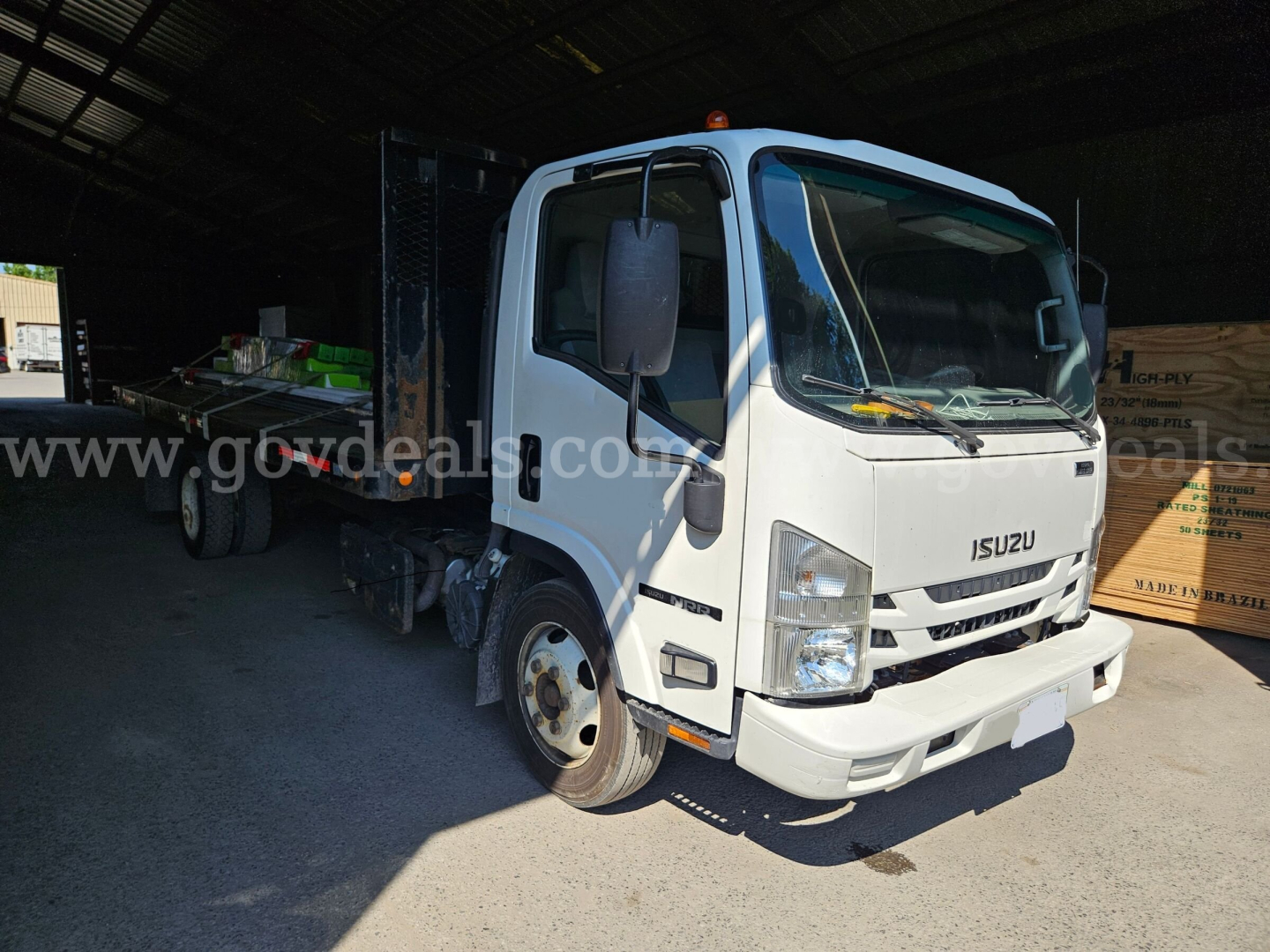 Isuzu NQR dump truck in a warehouse bay with front cab view, white color, VIN JALE5W169G7301492, stock 32136-91, category Dump, New/Used Used.