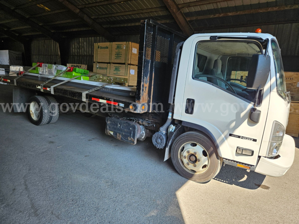 Isuzu NQR dump truck in a storage space showing cargo bed with pallets and boxes.