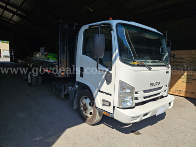 Isuzu NQR dump truck in a warehouse bay with front cab view, white color, VIN JALE5W169G7301492, stock 32136-91, category Dump, New/Used Used.