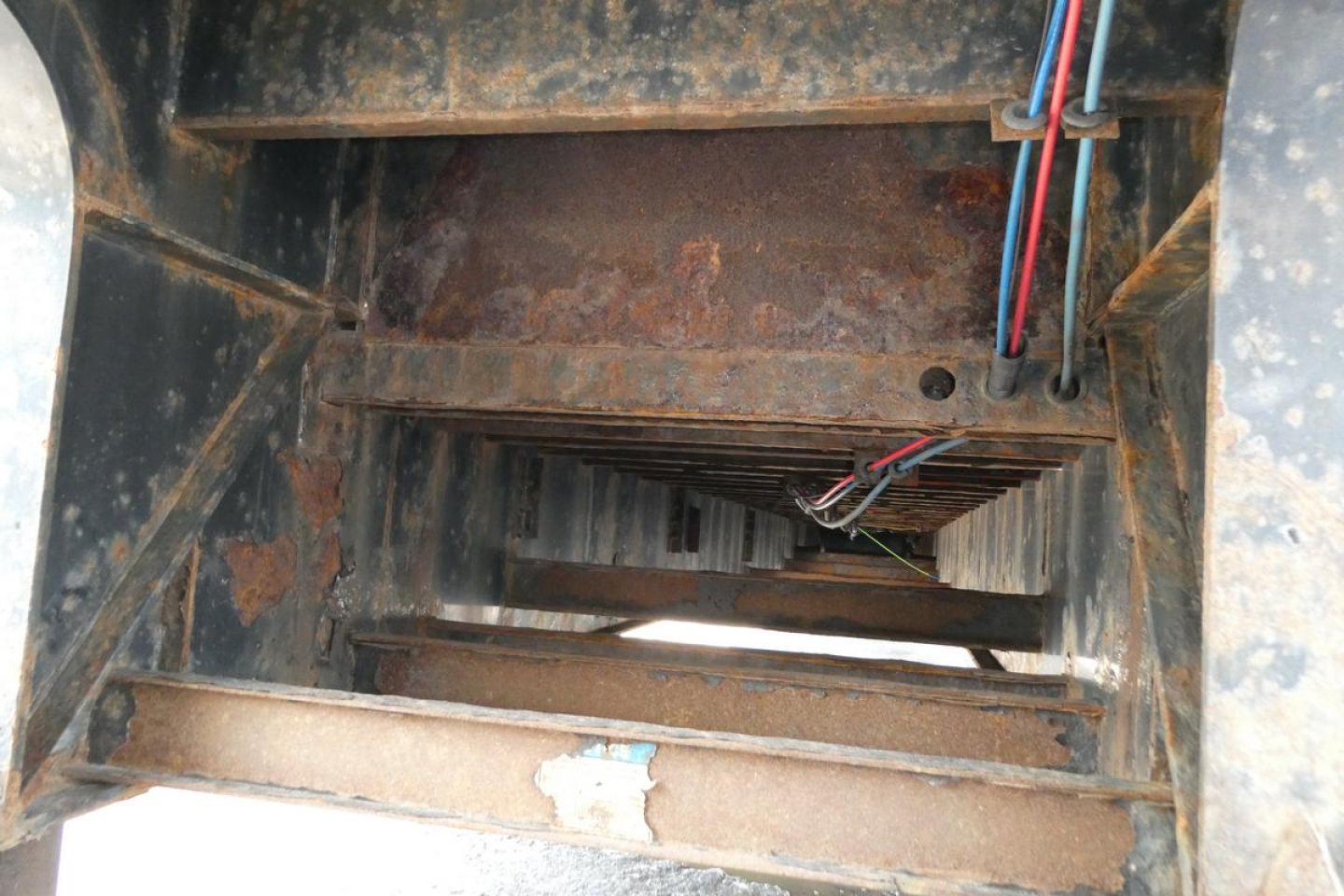 Interior of Fontaine HCITX22RSA trailer showing rusted steel deck and wiring harness, view through open access hatch with stair-like structure.