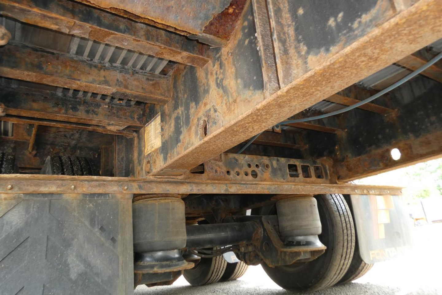 Trailer underside showing suspension rails and air springs of a Fontaine HCITX22RSA drop deck trailer.