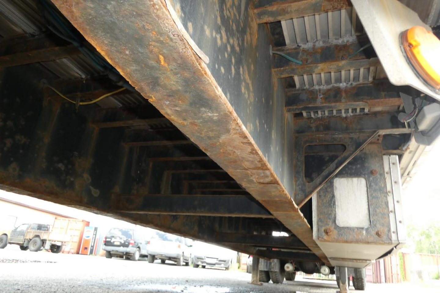 Underbelly of a Fontaine HCITX22RSA trailer showing steel beams and support frame with rust-like patina; visible bolts and underside components.