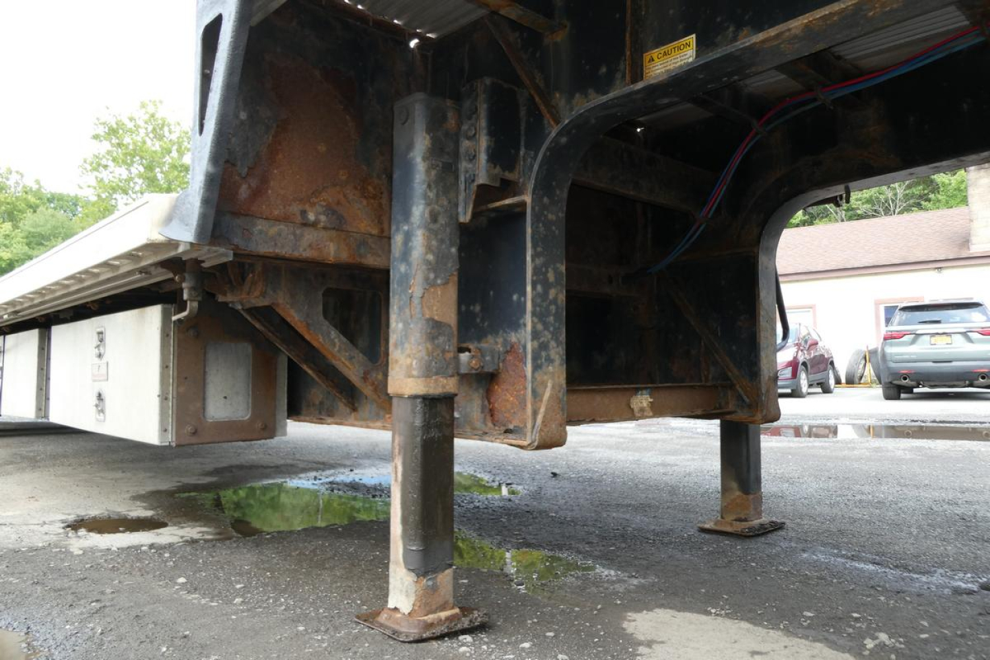Trailer landing gear and undercarriage showing metal frame with rust-toned components and stabilizing jacks.