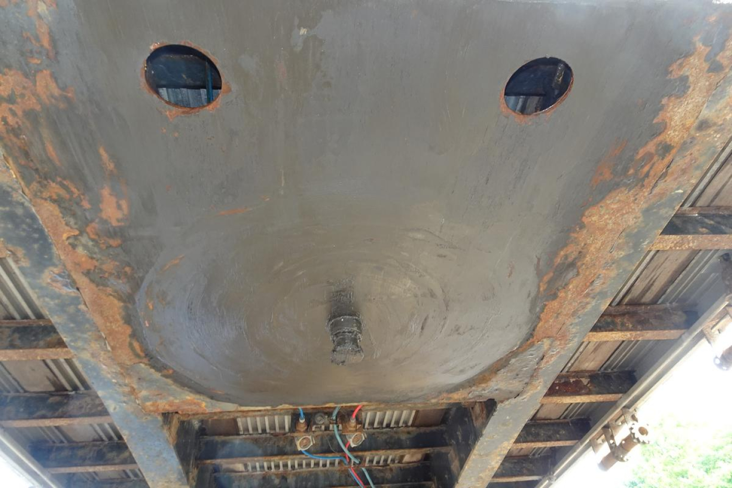 Underside of a Fontaine HCITX22RSA trailer showing circular underside recesses, rust patches, and wiring harnesses near the center.