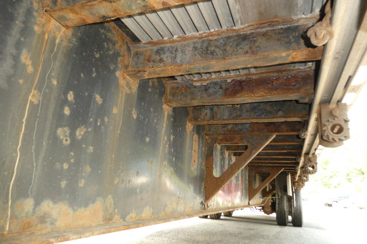 Underside view of a Fontaine trailer frame showing cross members and rusted steel structure in the undercarriage.
