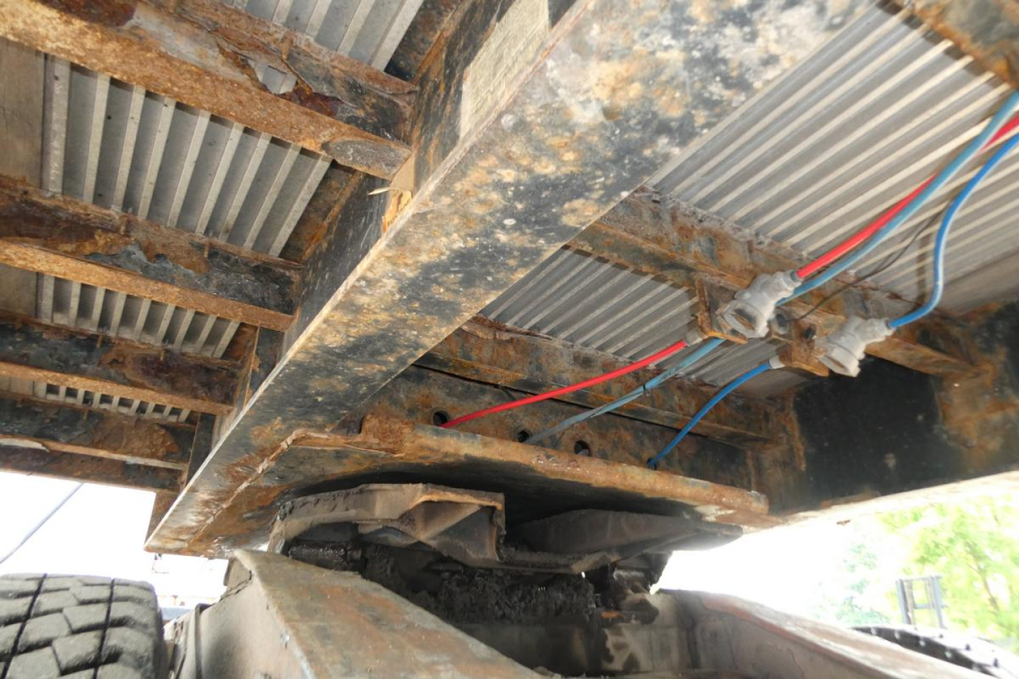 Underneath view of a Fontaine trailer frame showing exposed metal beams and wiring harness with red and blue hoses.