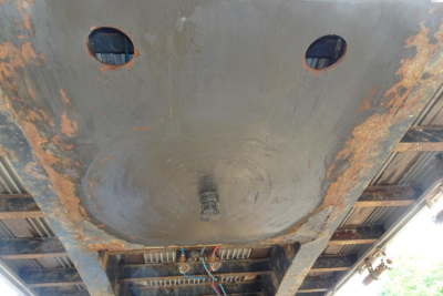 Underside of a Fontaine HCITX22RSA trailer showing circular underside recesses, rust patches, and wiring harnesses near the center.