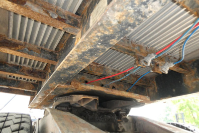 Underneath view of a Fontaine trailer frame showing exposed metal beams and wiring harness with red and blue hoses.
