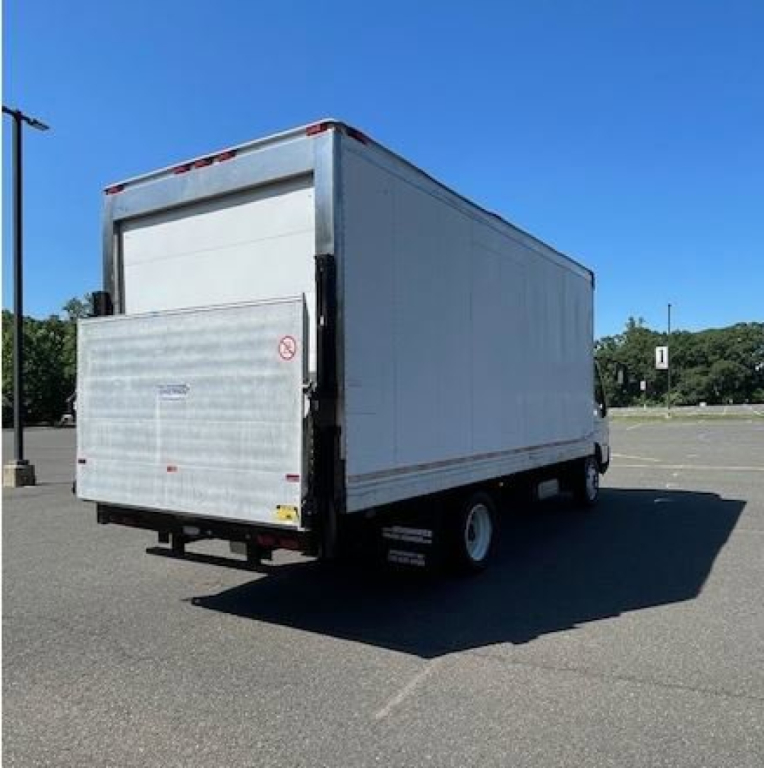 Truck rear view showing a white box van with a liftgate in a parking lot.