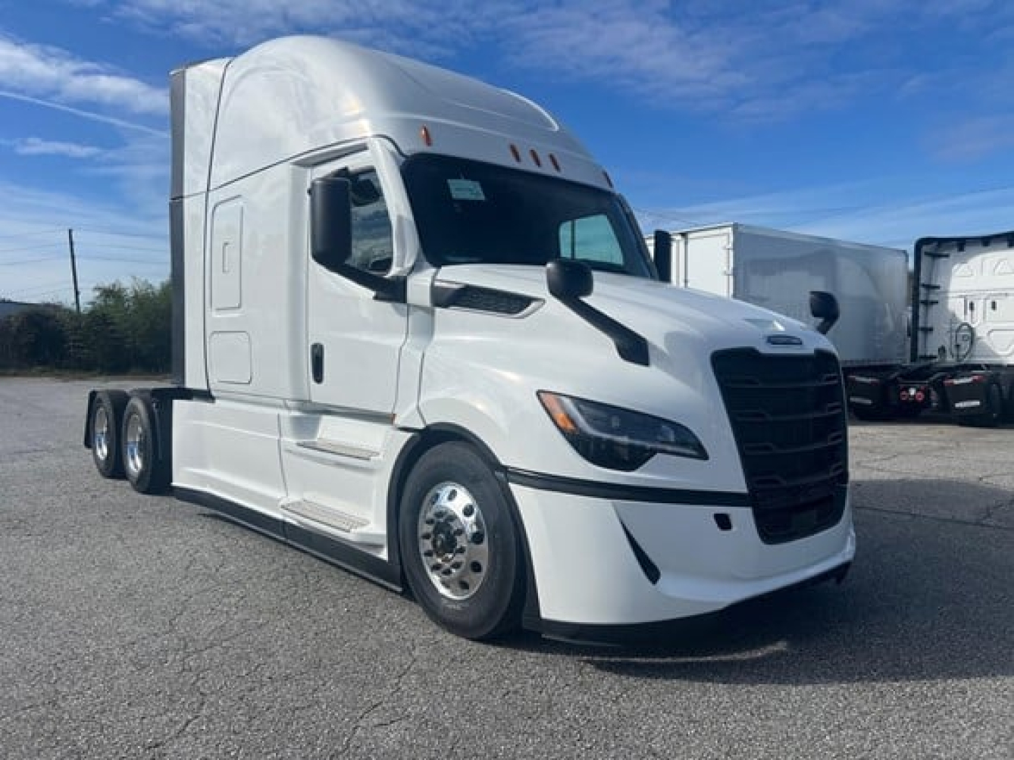 White Freightliner Cascadia 126 tractor in a parking lot, front-left view. No visible text on logo or decals.