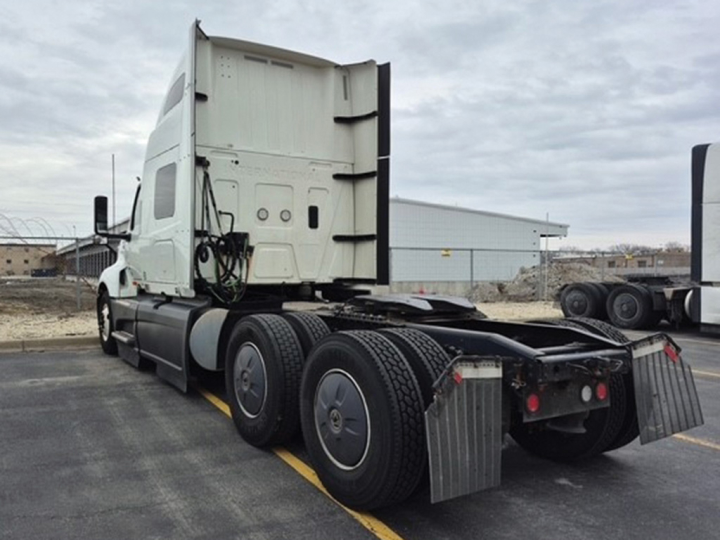 Truck cab and rear chassis of a used 2023 International LT625 tractor, side view showing dual rear axles, fifth-wheel area, and mud flaps.