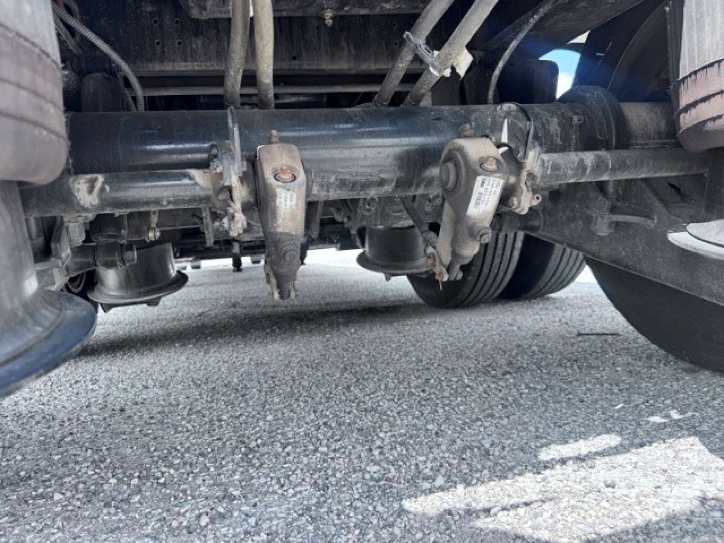 Underneath view of trailer suspension showing dual axle hubs and leaf springs.