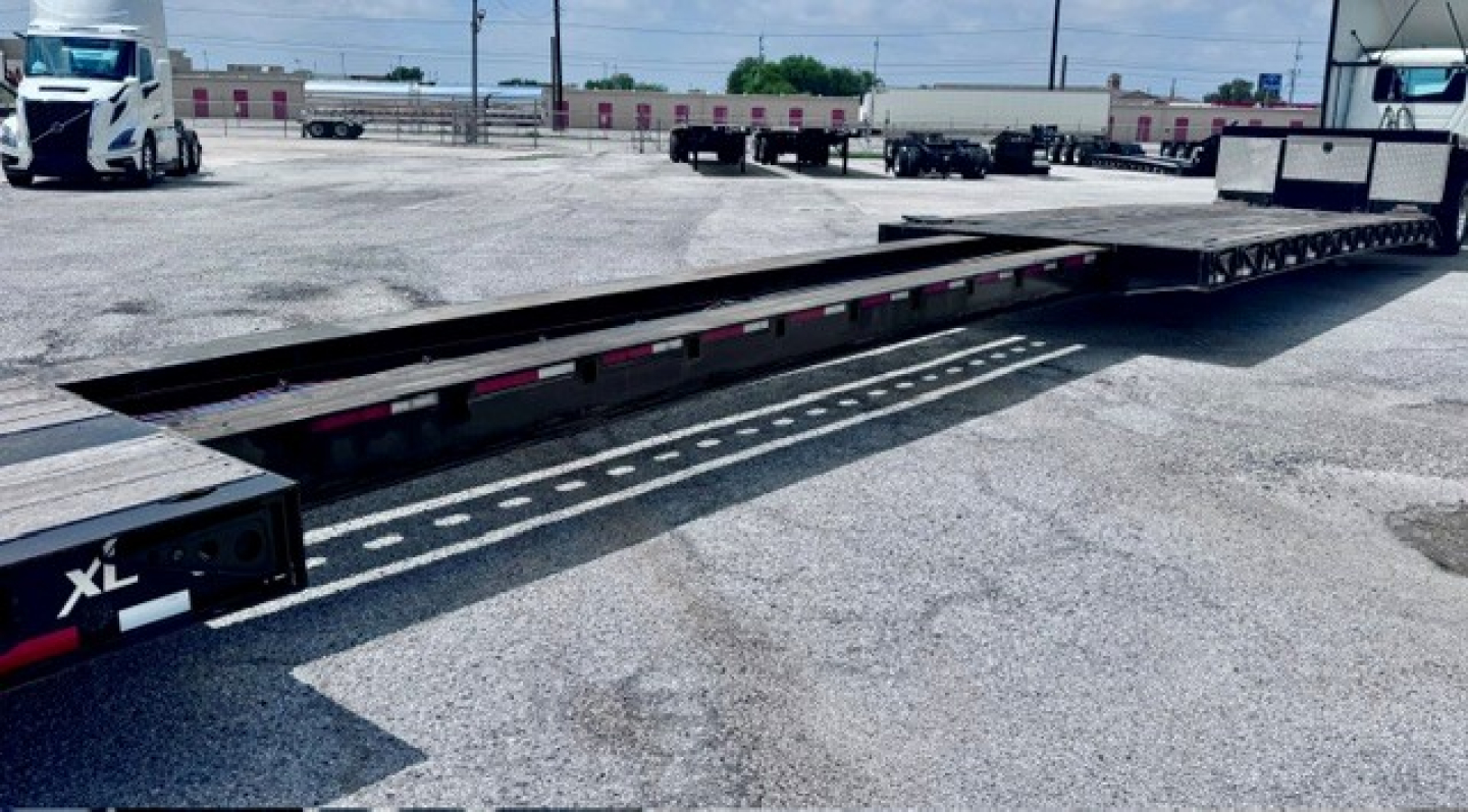 XL Specialized XL 80 MDE lowboy trailer showing long flatbed with black frame and reflective tape along the edge.