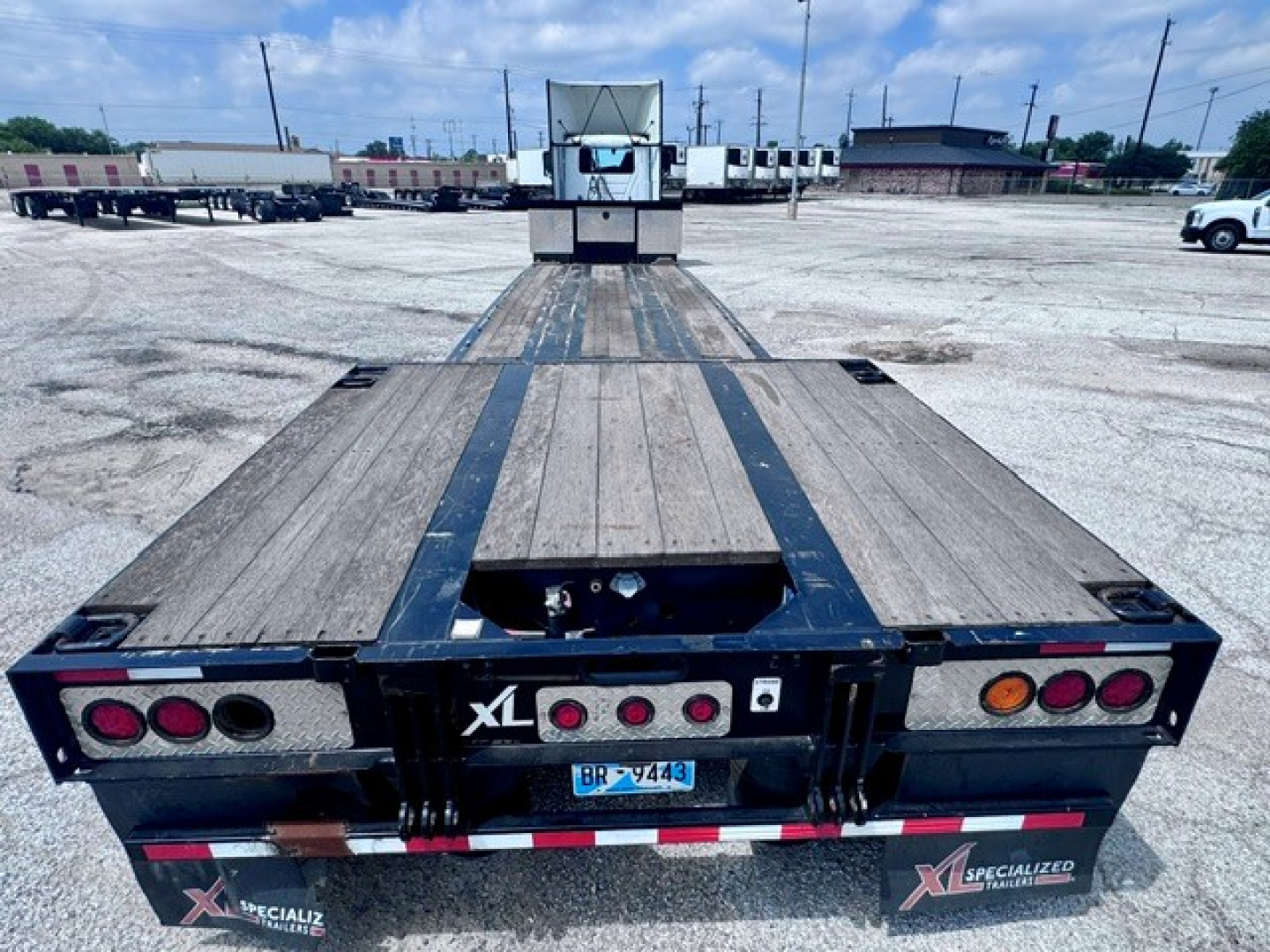 Trailer bed of a 2023 XL Specialized XL 80 MDE lowboy trailer showing steel deck, rear ramps, taillights, and branding. VIN 4U3J04820PL021916 and stock B3473 visible.