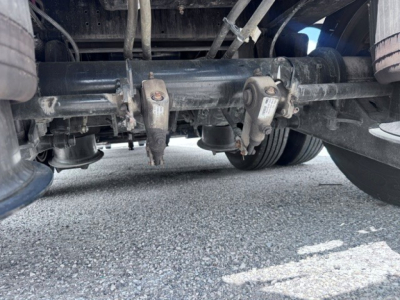 Underneath view of trailer suspension showing dual axle hubs and leaf springs.