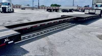 XL Specialized XL 80 MDE lowboy trailer showing long flatbed with black frame and reflective tape along the edge.