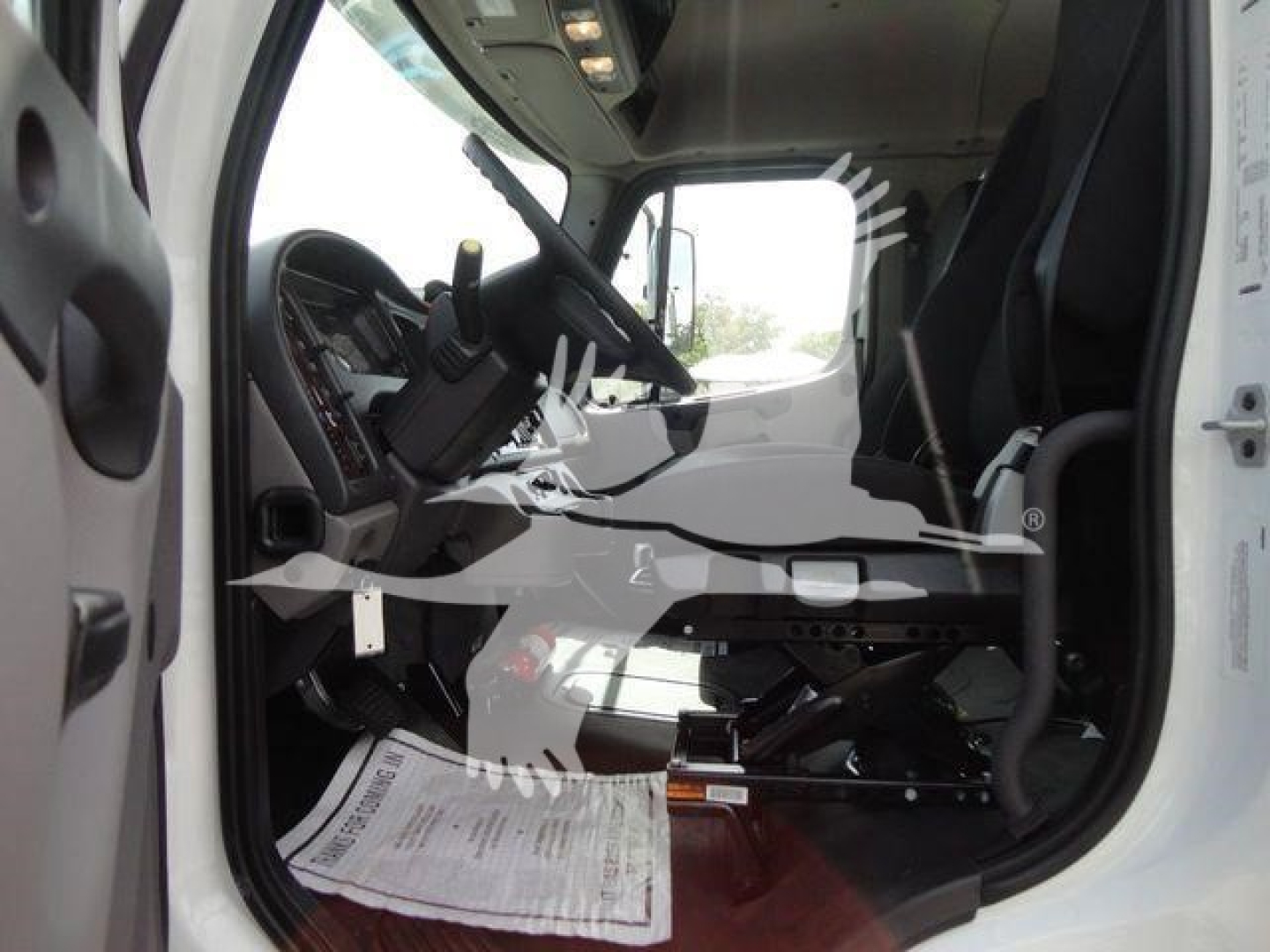 Truck cab interior of a 2027 Freightliner Business Class M2 showing driver seat, steering wheel, dashboard, and entry area.