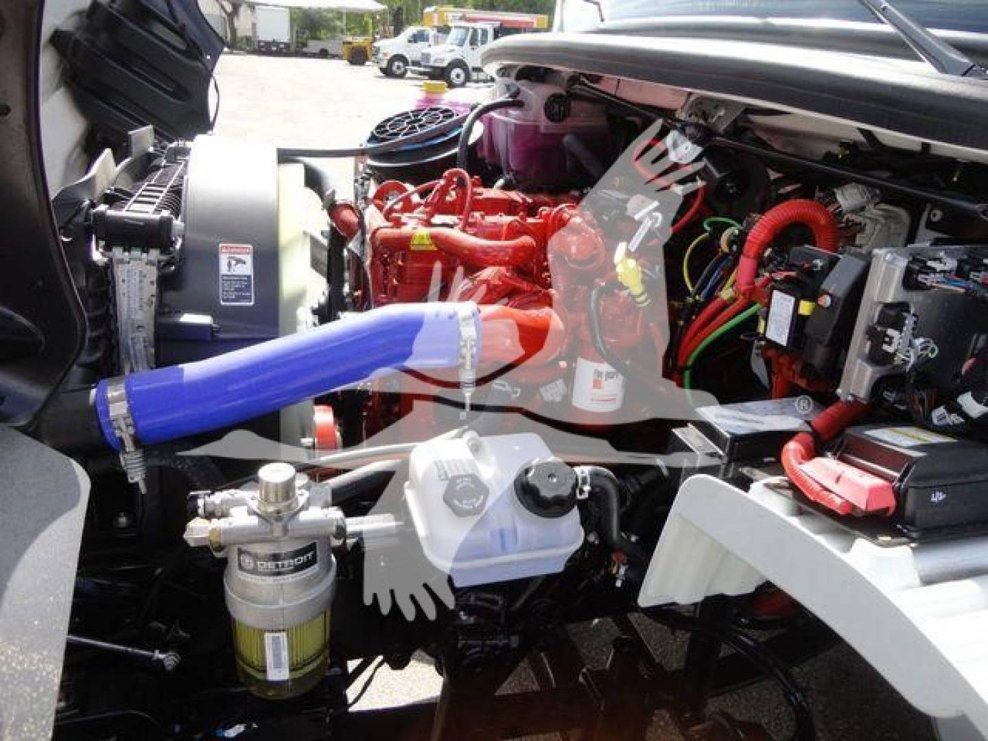 Truck engine bay with red engine block, various hoses, and blue radiator hose visible; components and wiring in view.