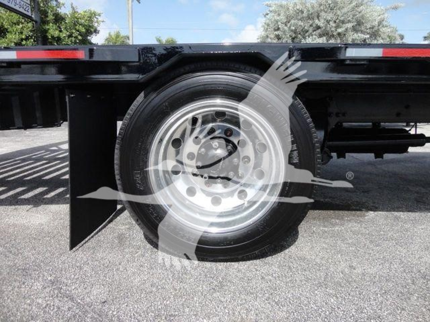 Rear wheel and undercarriage of a Freightliner Business Class M2 rollback truck showing a steel rim and tire with a black underbody panel.
