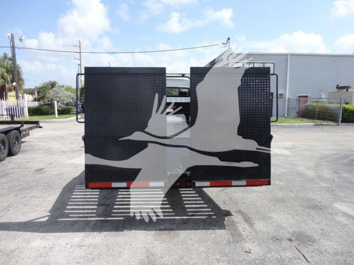 Back view of a Freightliner Business Class M2 rollback truck trailer with black rear doors and reflective tape.