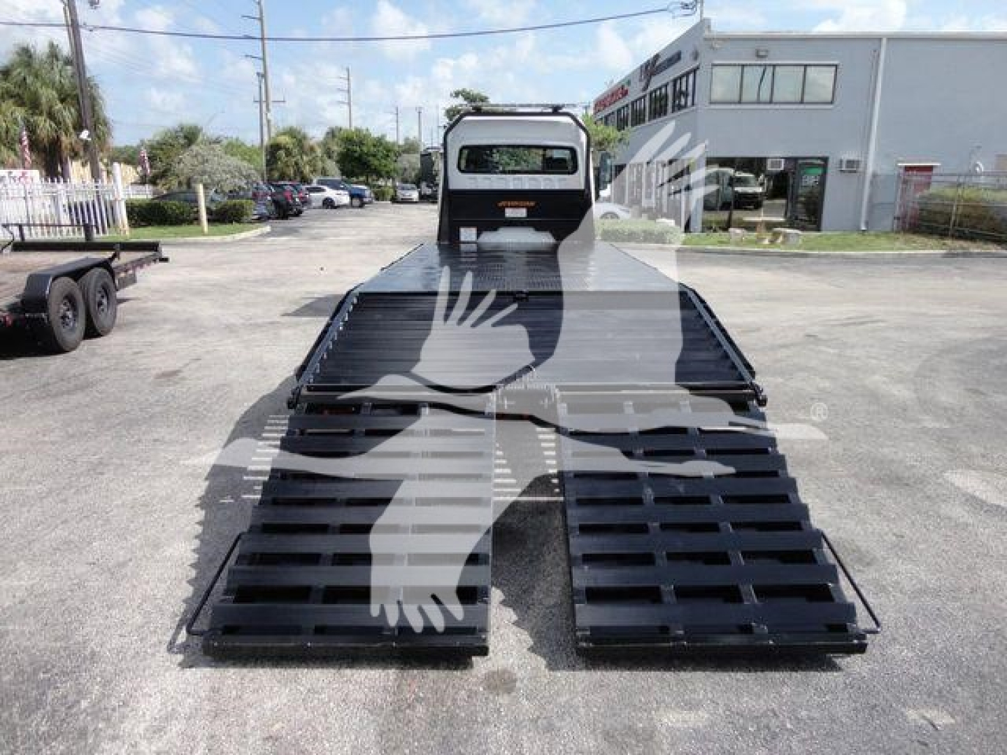 Freightliner Business Class M2 rollback truck bed with lowered ramps, front cab visible, outdoor dealership lot in background.