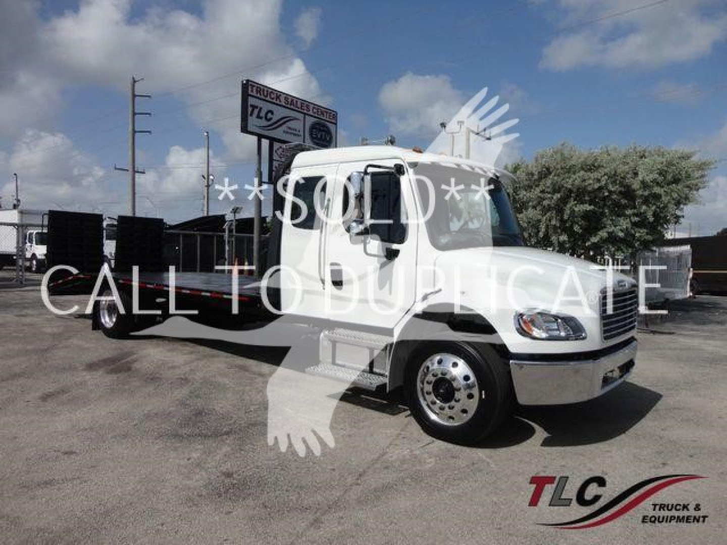 Truck with a rollback bed, Freightliner Business Class M2, white cab, long wheelbase, TLC logo in lower right corner.