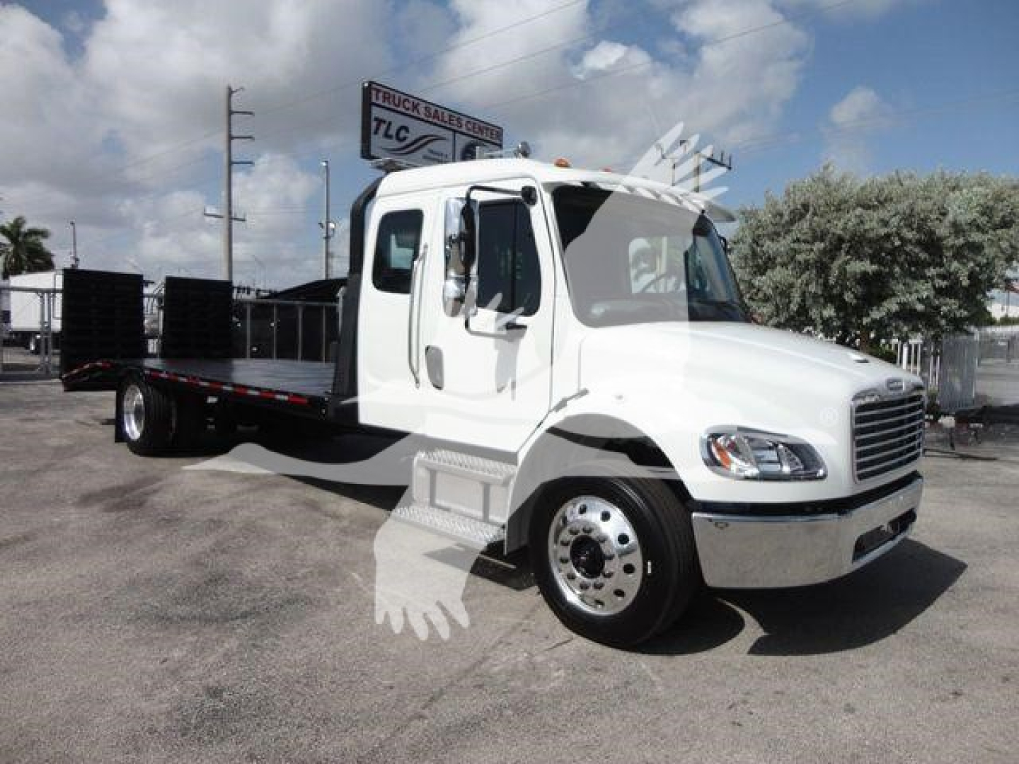Freightliner Business Class M2 rollback truck with white cab and flatbed, side view showing dual rear wheels and flatbed platform.