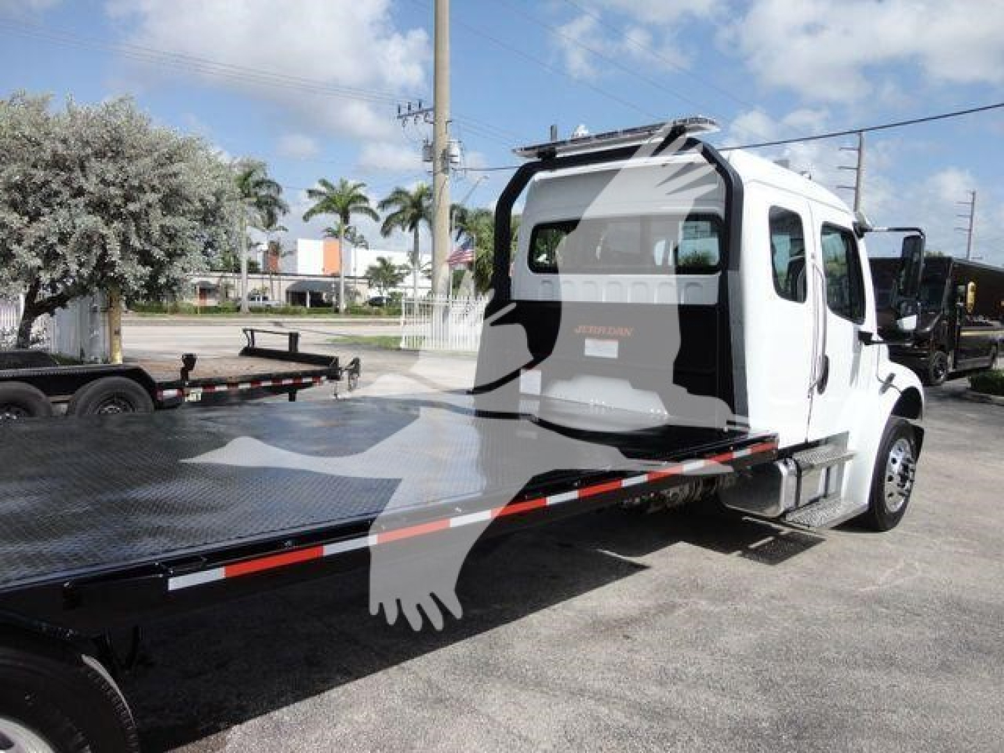 Truck cab and flatbed rollback tow truck from rear/side angle showing Freightliner Business Class M2 with flatbed platform.