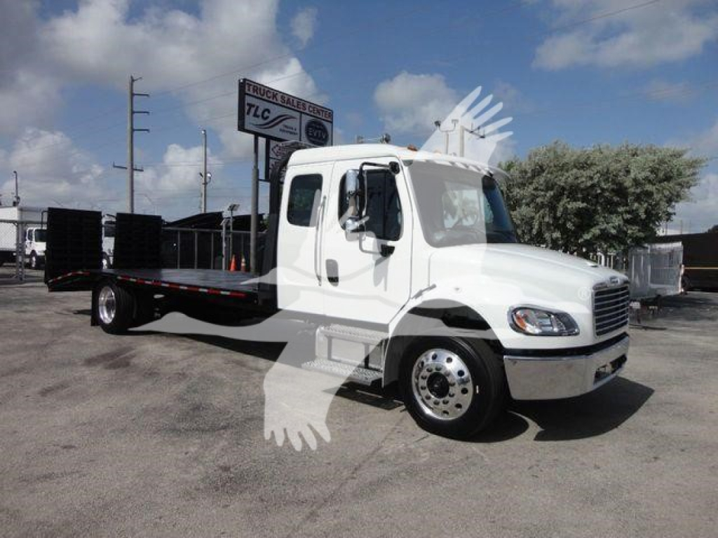 Freightliner Business Class M2 rollback truck in white, side profile view, flatbed bed with black railing, cab doors and large side mirrors visible, dealership lot in background