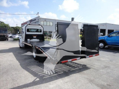 Freightliner Business Class M2 rollback truck in yard showing loading bed and rear stabilizers.